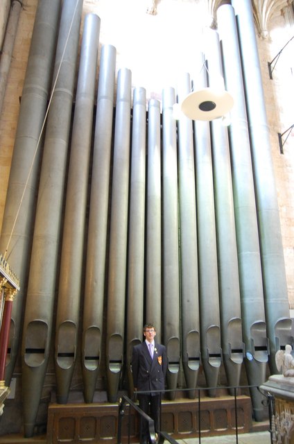 photograph of organist in front of organ pipes