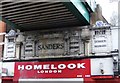 Two shop signs under railway bridge