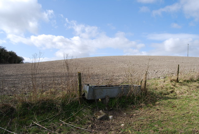 A chalky field behind a water trough