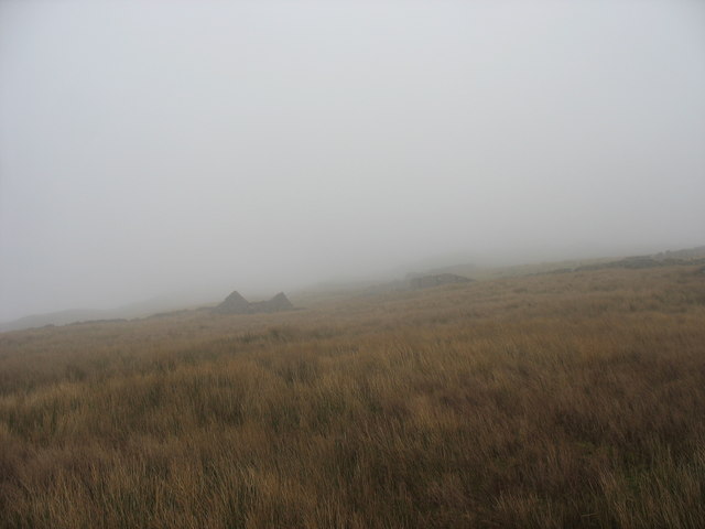 View across a foggy boggy mountainside towards a ruined barn