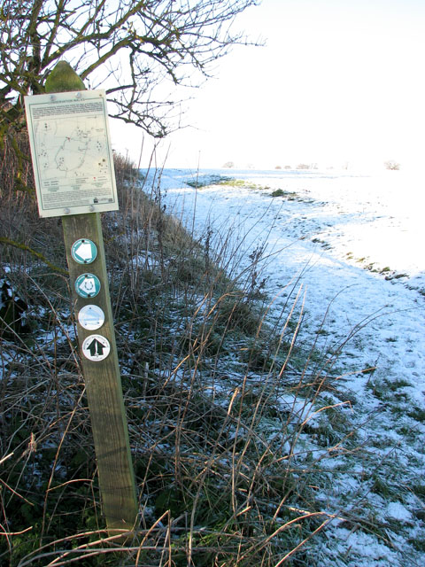 Footpath marker and map beside derelict farm buildings