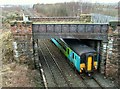 Train passing under disused bridge