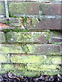 Damaged benchmark on wall by garages on Stratford Road