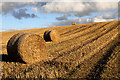 NT5319 : A stubble field with round bales at Hassendean Hill by Walter Baxter