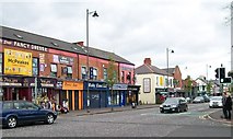 J3273 : A row of small shops on the Falls Road by Eric Jones