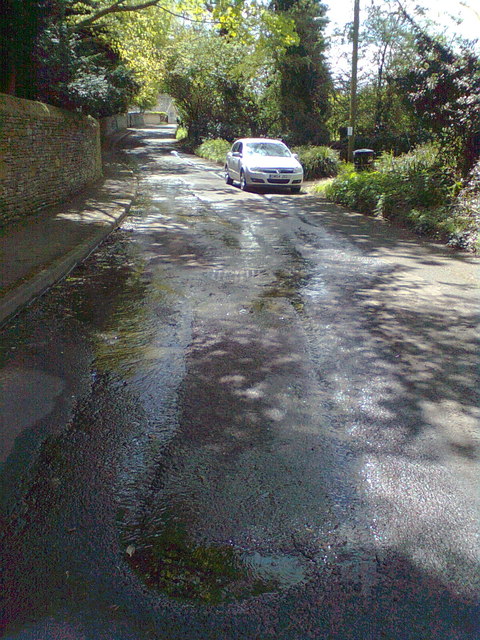 Road near Tite Tap, with spring water welling through tarmac