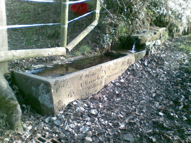 Stone water trough with an inscription and a bench mark