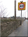 Stone wall alongside the B5119, and a bench mark