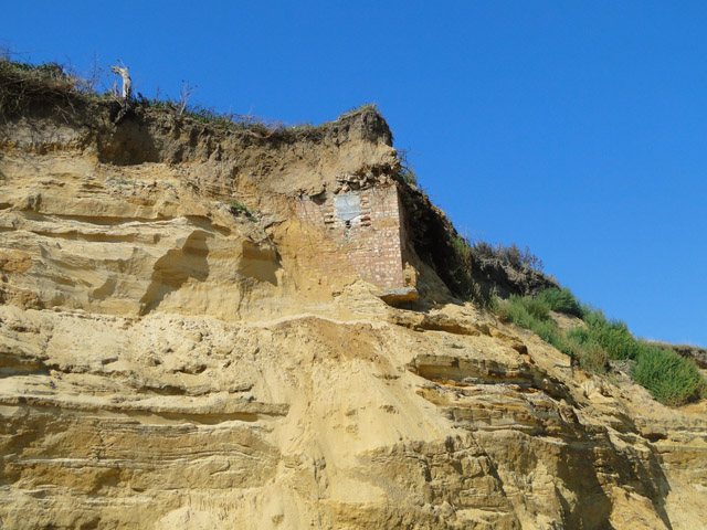 Subterranean building revealed in cliff-face, from the beach
