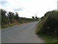 Lane looking east, footpath sign leaning over on the left of the picture