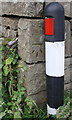 Benchmark on barn at Dolly Farm beside verge marker