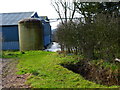 Footpath approaches yard on minor road