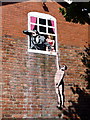 Naked man hanging from window