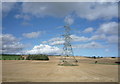 NT8739 : Pylons in stubble field near Cornhill on Tweed by JThomas