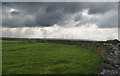 A wall, a wind farm and a threatening sky