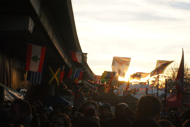 View of flags against the setting sun in the Portobello Road Winter Festival from Acklam Road