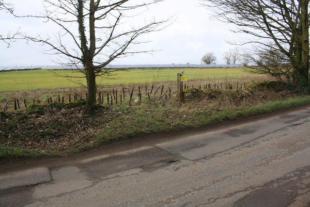Isolated gatepost beside road with solar panel farm in background