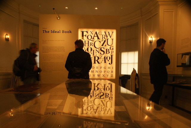 View of The Ideal Book information board reflected in a glass case in the William Morris Gallery