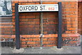 Benchmark under Oxford Street name sign