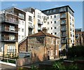 Cottage dwarfed by block of flats