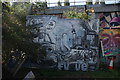 View of street art on a piece of hoarding next to the London Overground line in the Nomadic Community Garden