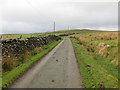 Minor road between stone wall and open ground near Parc-newydd