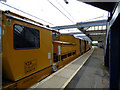 A yellow machine passing through Troon railway station