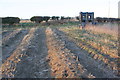 Water tank in hedgerow in ploughed field