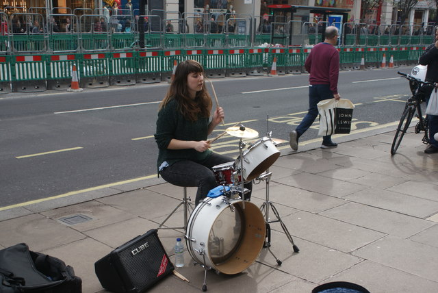 View of street drummer Lady Banana performing outside John Lewis on Oxford Street