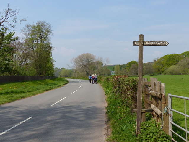Footpath sign and walkers on the road