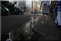 View of a building on the corner of Weston Street and Snowsfields reflected in a puddle on Weston Street