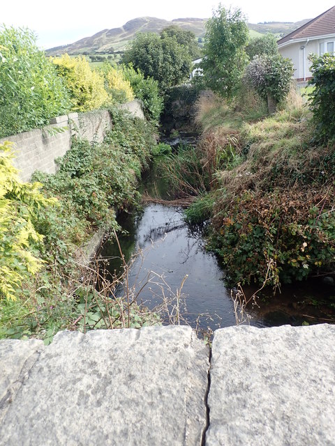 A canalised section of the Camlough River diverted round the back of a row of semi-detached houses