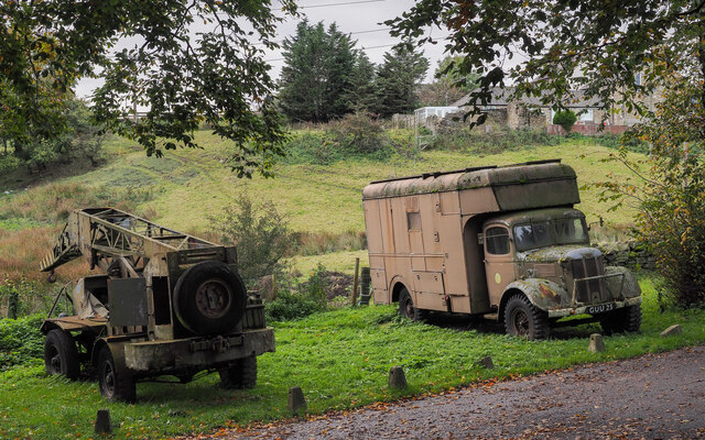 Military-style vehicles beside farm road