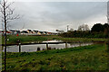 A pond with houses on Penhill View in the background