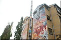 View of street art on a lamp post and the side of the Station House hostel on Pedley Street