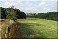 View from a stile, of footpath and woods beyond