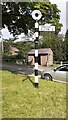 Finger signpost  on grass island and bus shelter in Glassonby