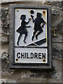 Close look at old road sign for "children playing" - on a wall at St Briavels