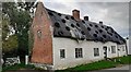 Thatched house with roof held with tyres on west side of Rotherby Lane