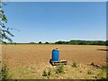 Blue drum barrel in the corner of a field