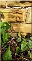 Weathered benchmark on east side of path running parallel to Wood Close