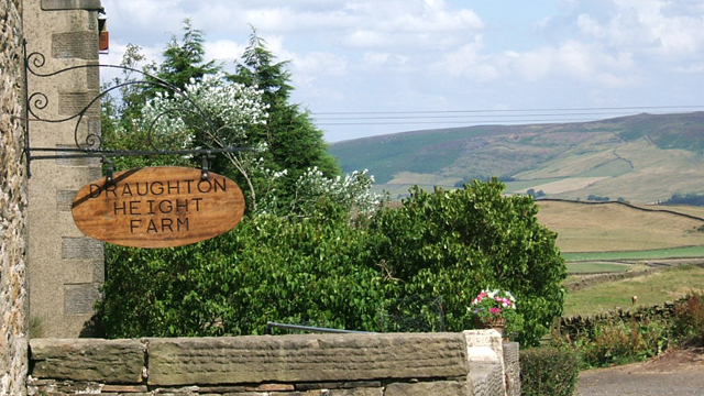 Name plate at front of farm and riding stables, with hills to north east in background