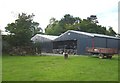 Another view of Cefn farm, showing a trailer, excavator scoop, silage bales and woodpile