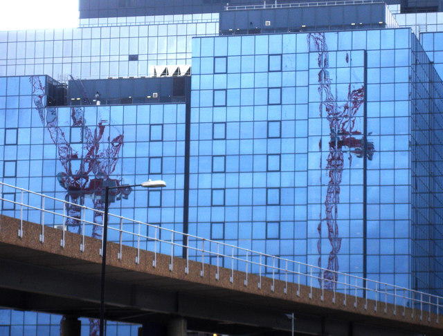 Cranes reflected in a wall of glass