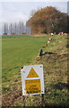 Warning sign at grassy landing strip - no fence