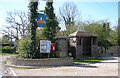 A pub sign, telephone box, post box, notice board and bus shelter