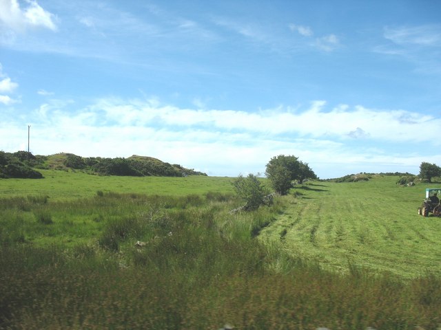 Cutting hay on a small meadow in area of small hills and rock outcrops