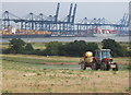 Tractor spraying in field overlooking the Orwell and Felixstowe docks